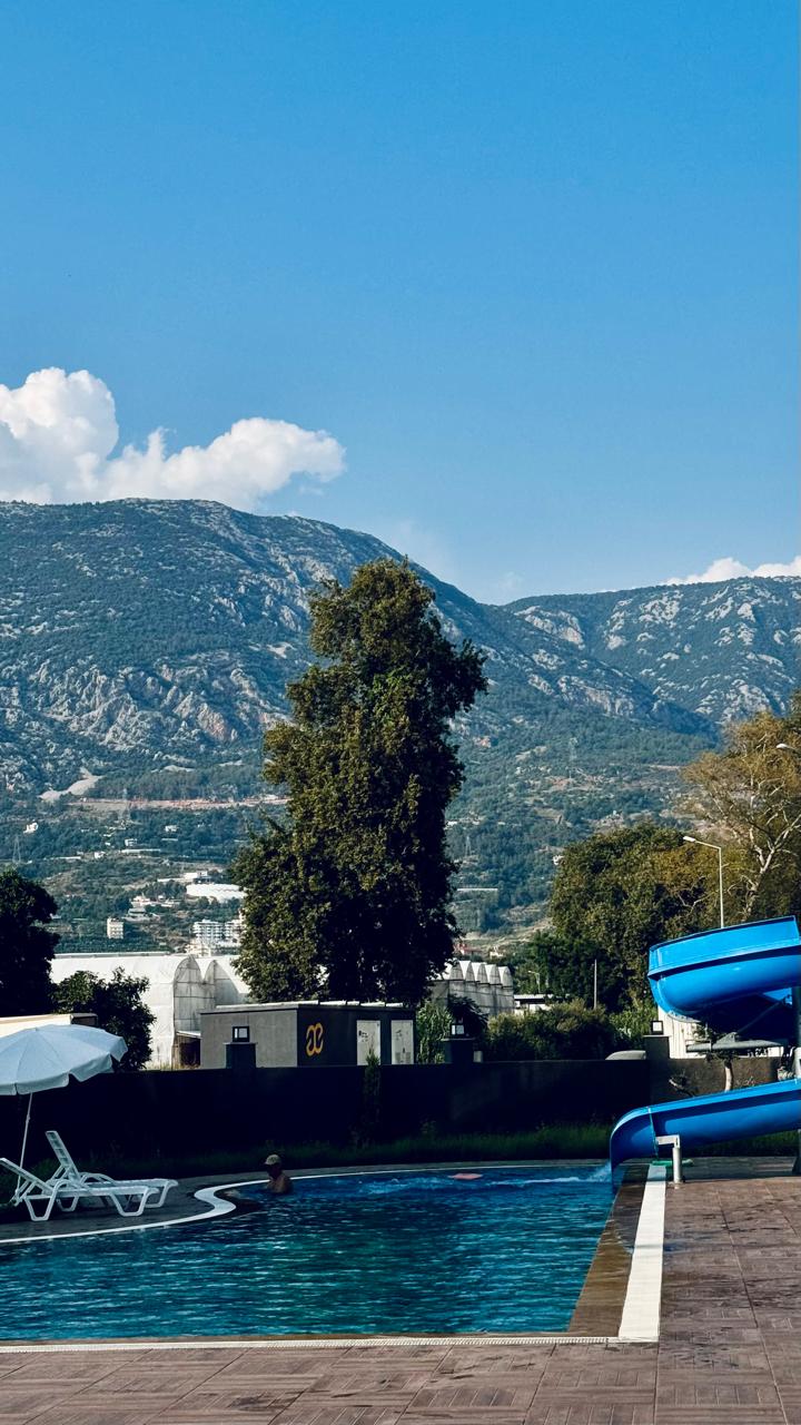 Kaydıraklı ve şezlonglu açık havuz, denize yakın yerde satılık dairelerin bulunduğu komplekste