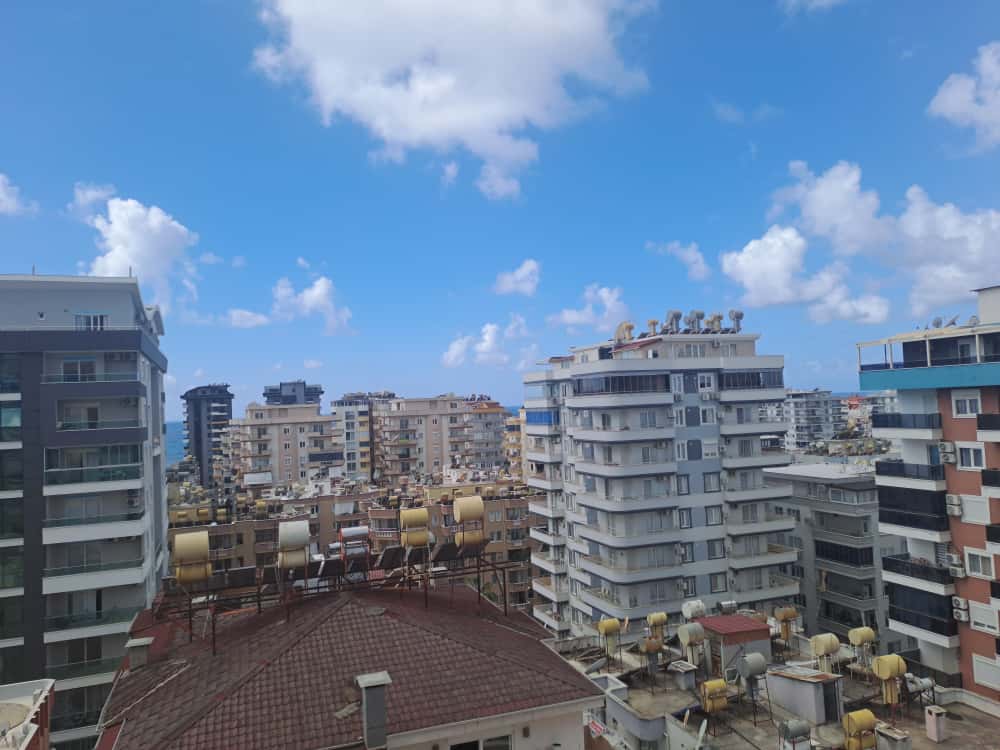 Cam balkonlu konutların şehir panoraması ve öndeki kırmızı kiremit çatı, Alanya’daki daireden