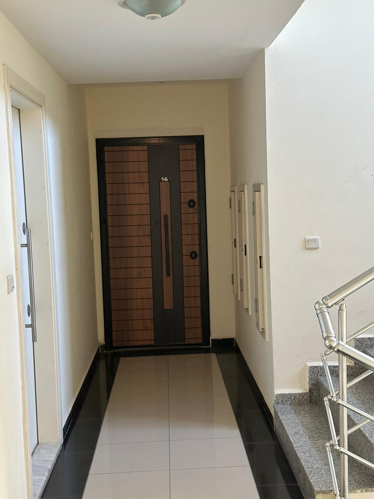 Granit basamaklı merdiven sahanlığı ve ahşap detaylı daire kapısı, Mahmutlar’da