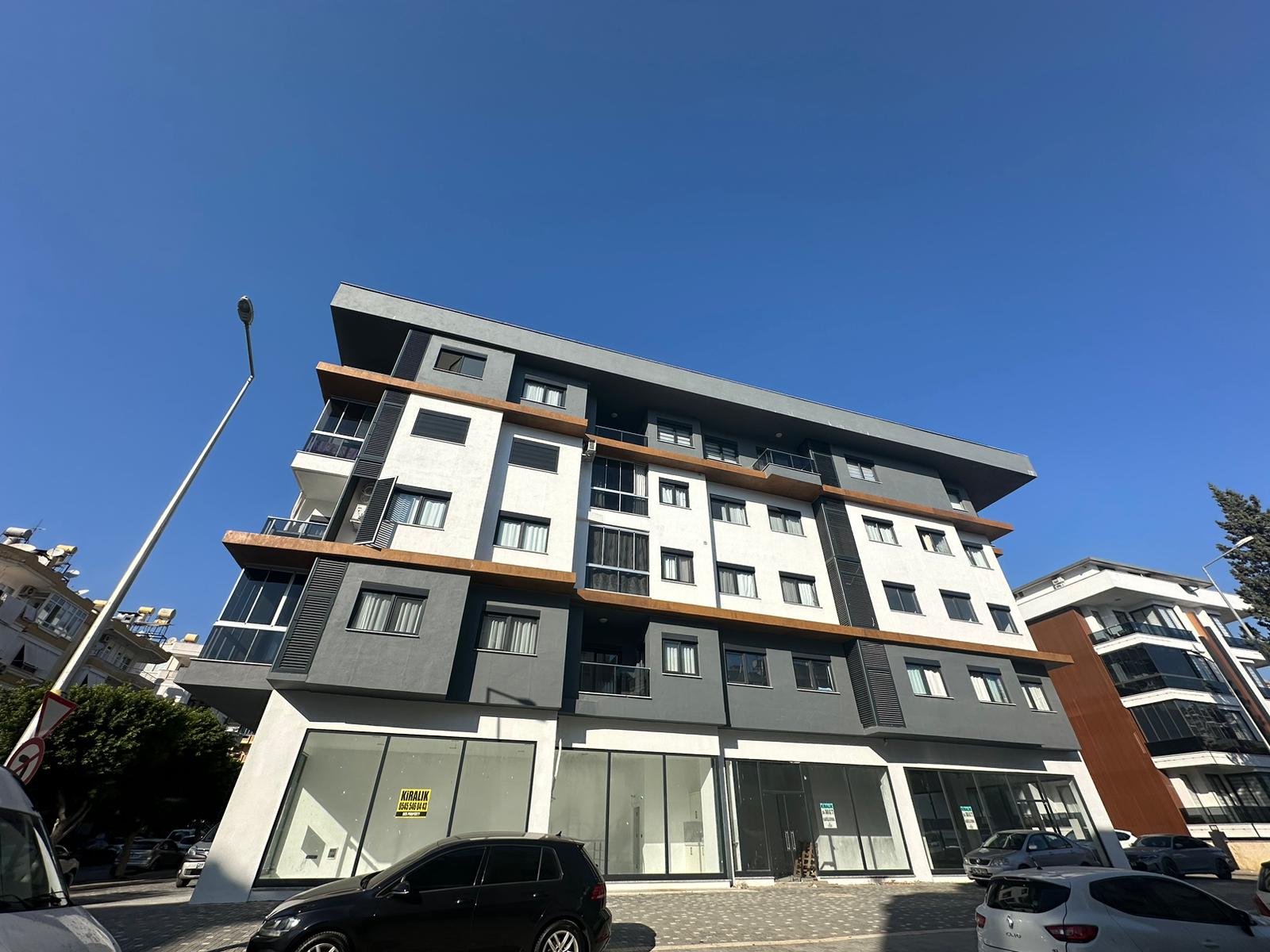 Alanya’daki dairelerin bulunduğu rezidansın cam balkonlu beyaz grafit cephesi ve vitrinleri