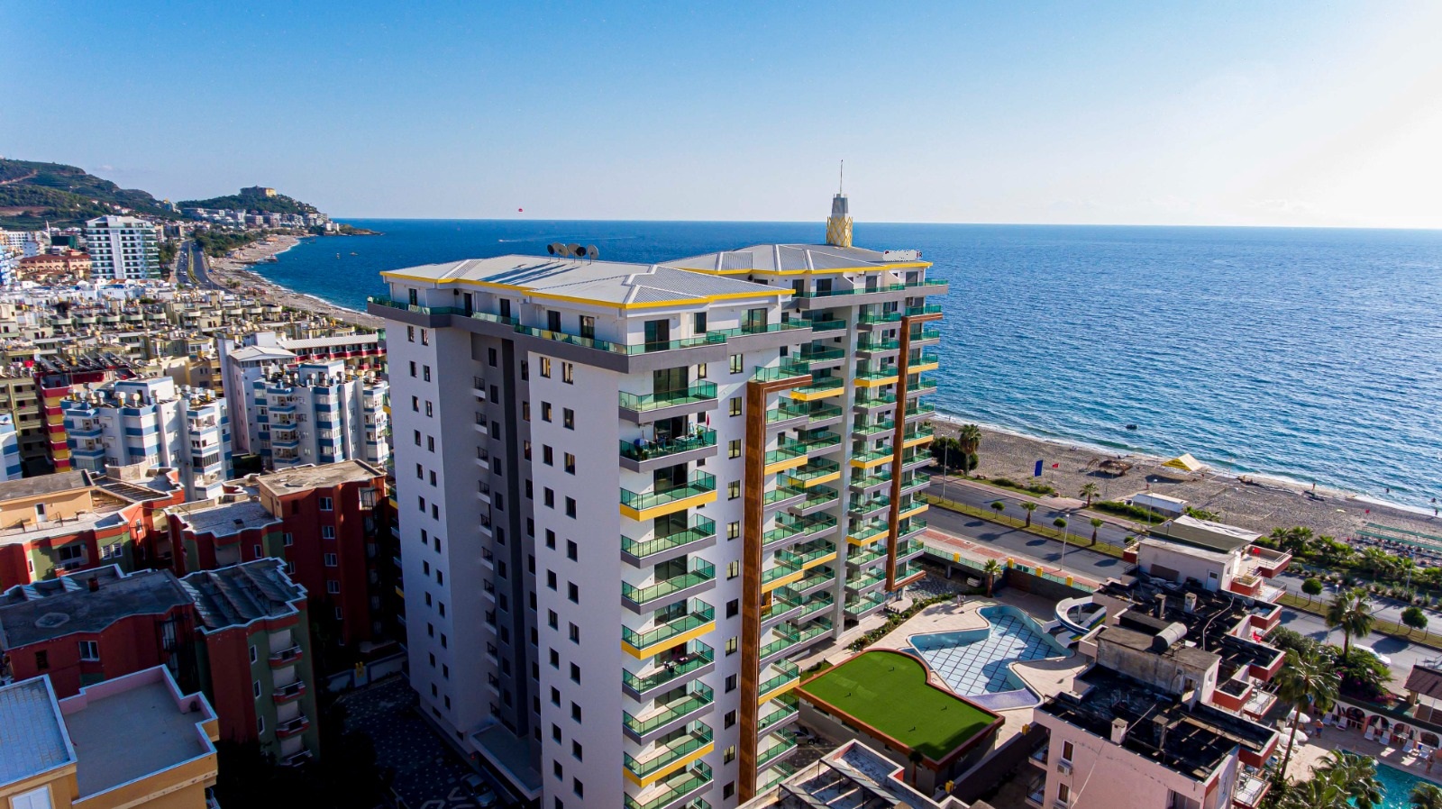 Deniz gerisindeki yüksek blok ve çevresindeki havuz, Alanya’da Türkiye’de dairelerin bulunduğu komplekste