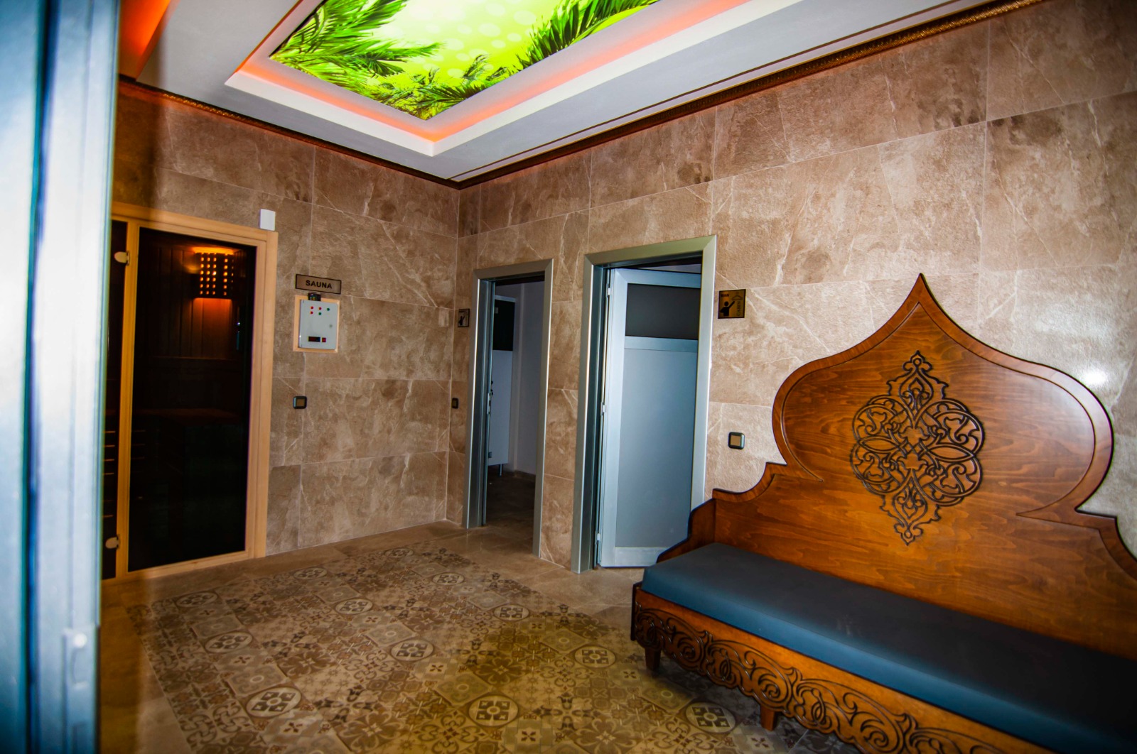 Spa alanında sauna girişi, oymalı ahşap sedir ve sıcak tavan aydınlatması daire sakinleri için