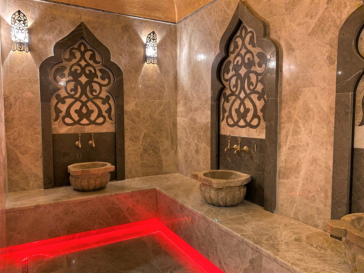 Hamamda kırmızı aydınlatmalı mermer platform ve iki taş kurna, Alanya’da dairelerin bulunduğu komplekste