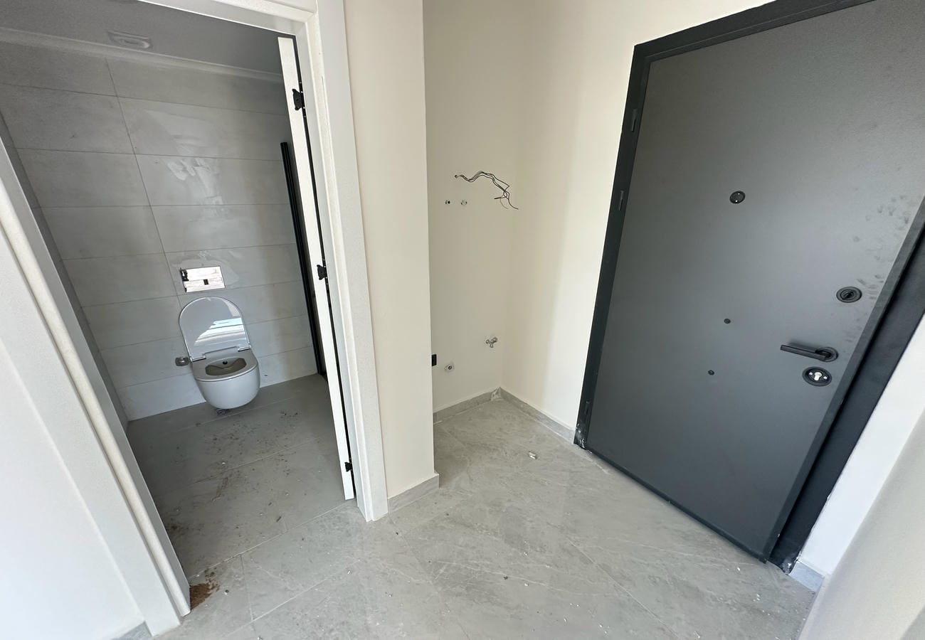 Daire girişinde gri kapı, banyoya açık geçiş ve beyaz iç kapılar
