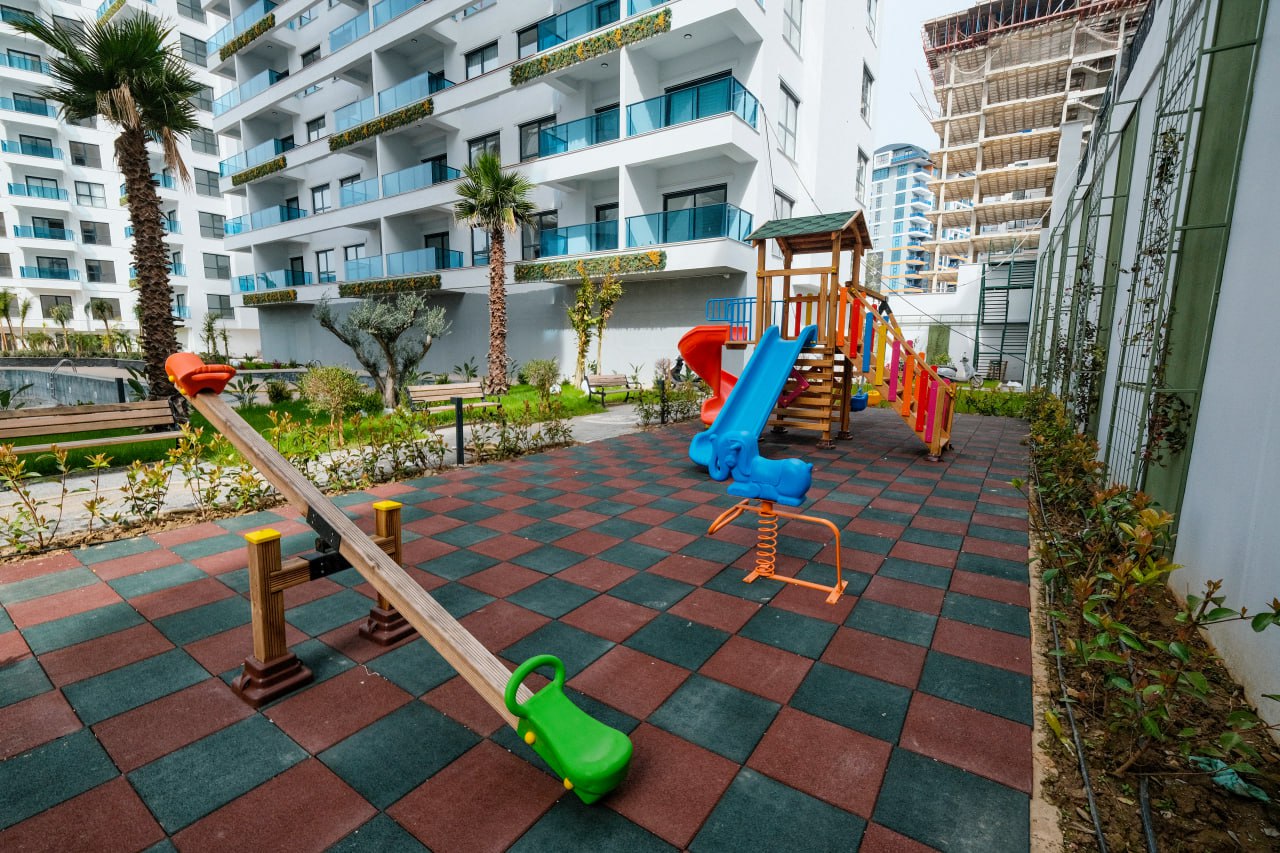 Mahmutlar’da dairelerin bulunduğu sitede ahşap oyun grubu ve mavi kaydıraklı çocuk parkı