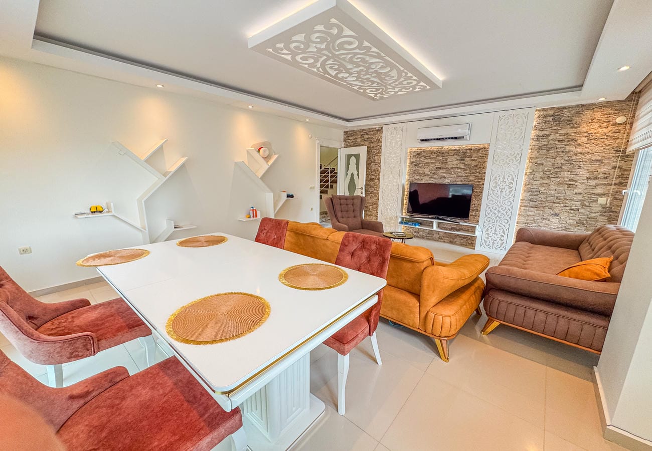 Bordo sandalyeli salon-yemek alanı ve turuncu koltuk, Türkiye’de satılık konutun içinde