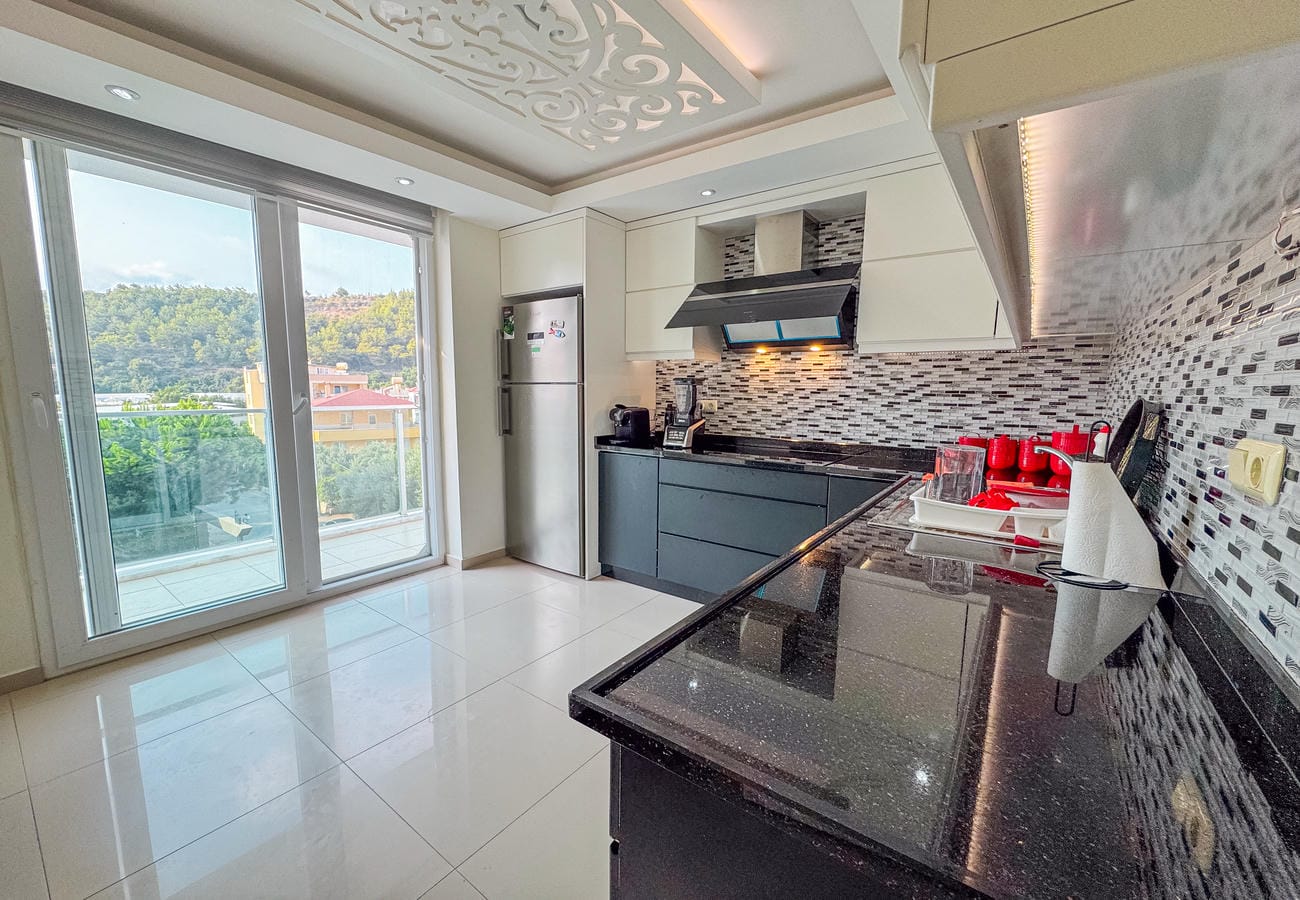 Siyah tezgâhlı köşe mutfak ve mozaik backsplash, penthouse dairede