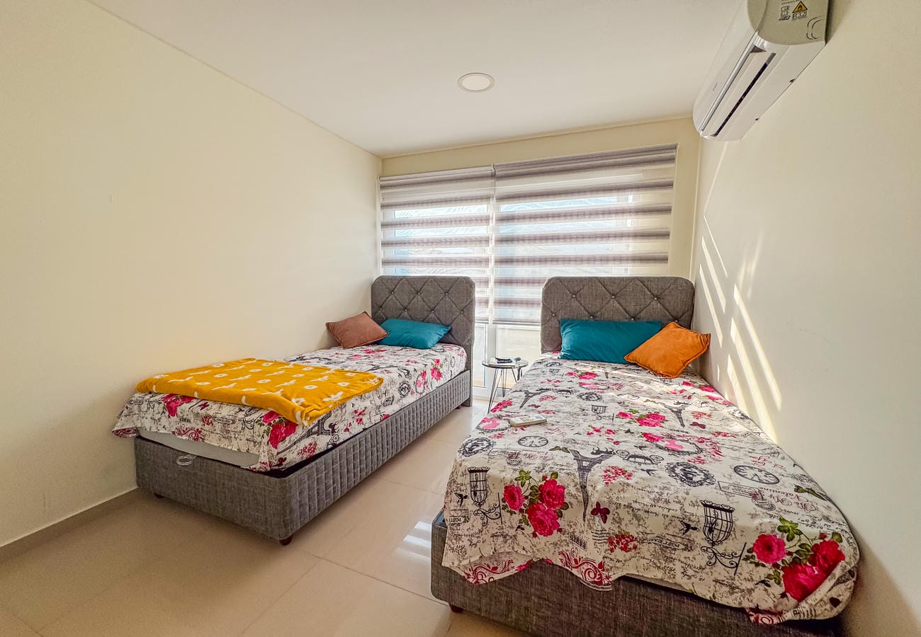 Çiçek desenli örtülü iki tek kişilik yatak ve kapitone başlık, penthouse yatak odasında