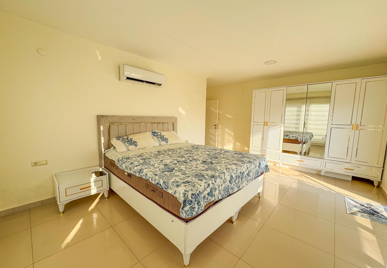 Yüksek başlıklı çift kişilik yatak ve aynalı beyaz gardırop, penthouse yatak odasında