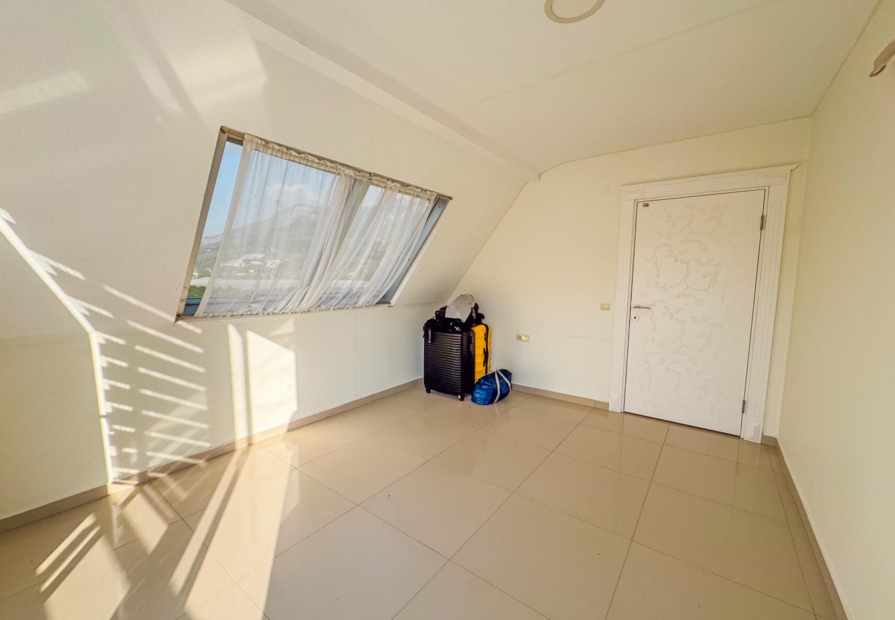 Eğimli pencereli boş oda ve bej büyük ebatlı zemin karoları, penthouse dairede