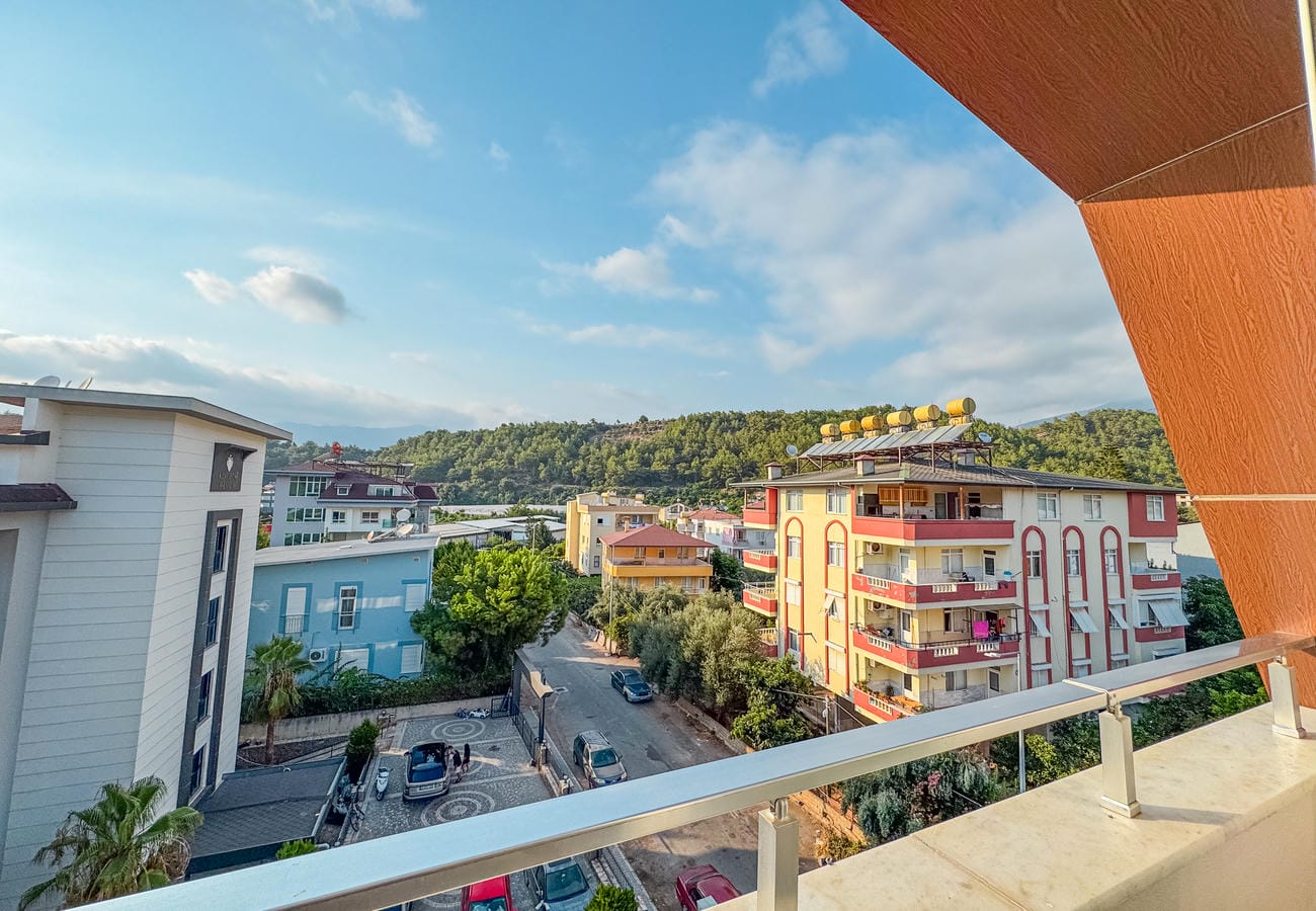Metal korkuluklu balkondan sokak, binalar ve yeşil tepelere panoramik bakış, rezidansta