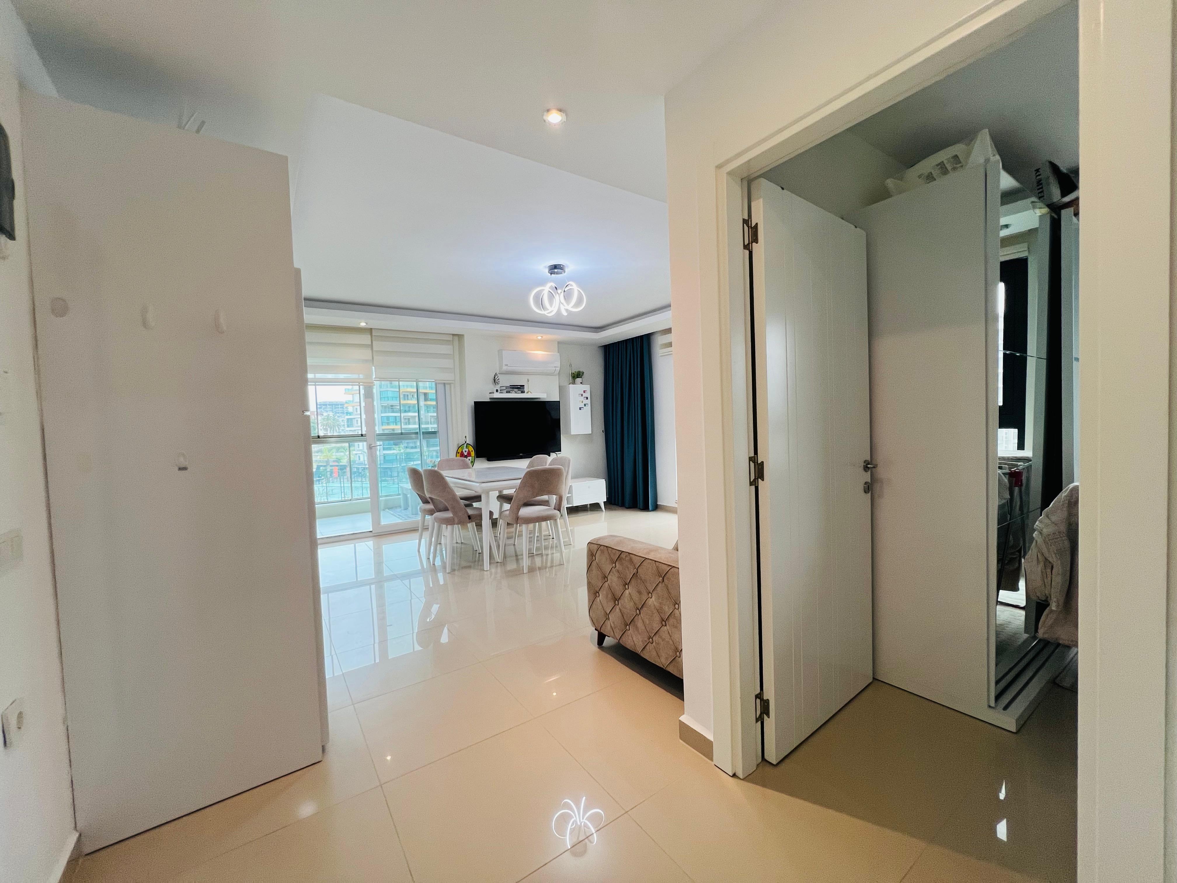 Bright hallway with a mirrored wardrobe door and a view into the living room of an apartment in Avsallar