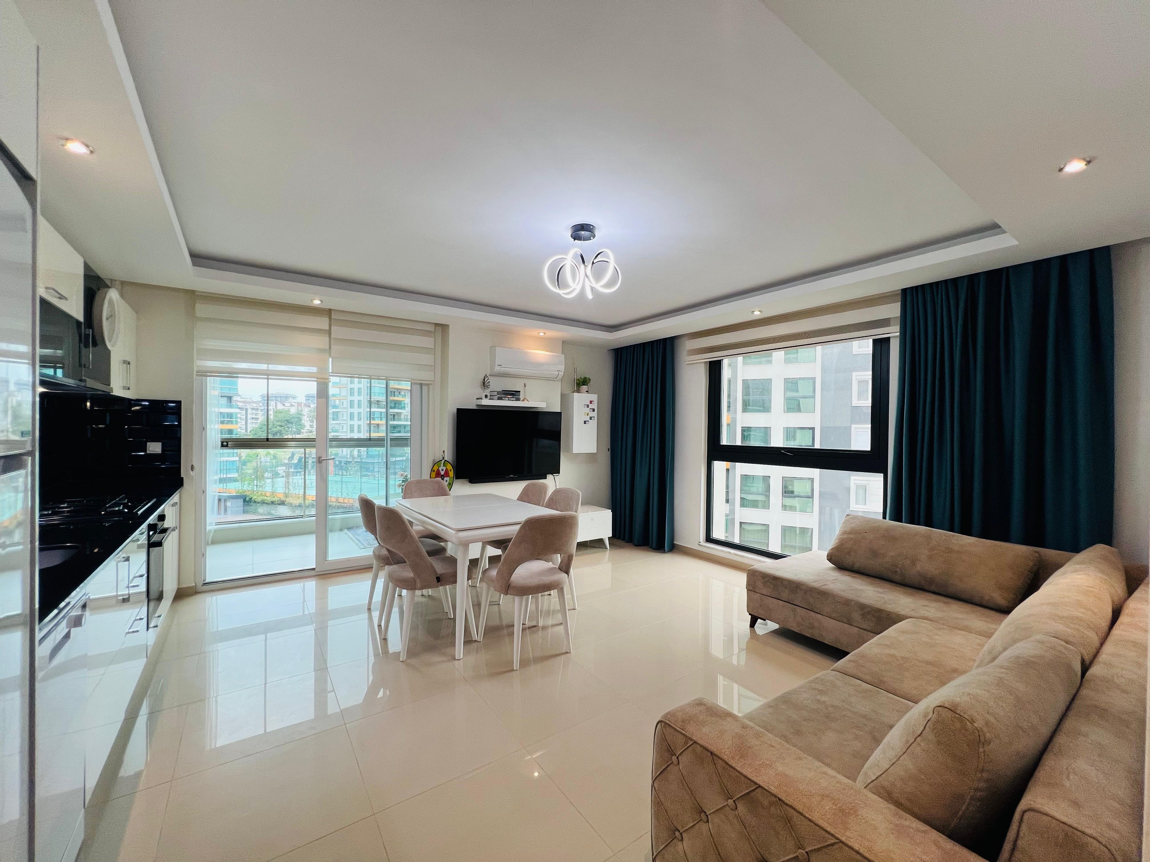 Kitchen-living room with a beige corner sofa and white kitchen cabinets in an apartment in Turkey