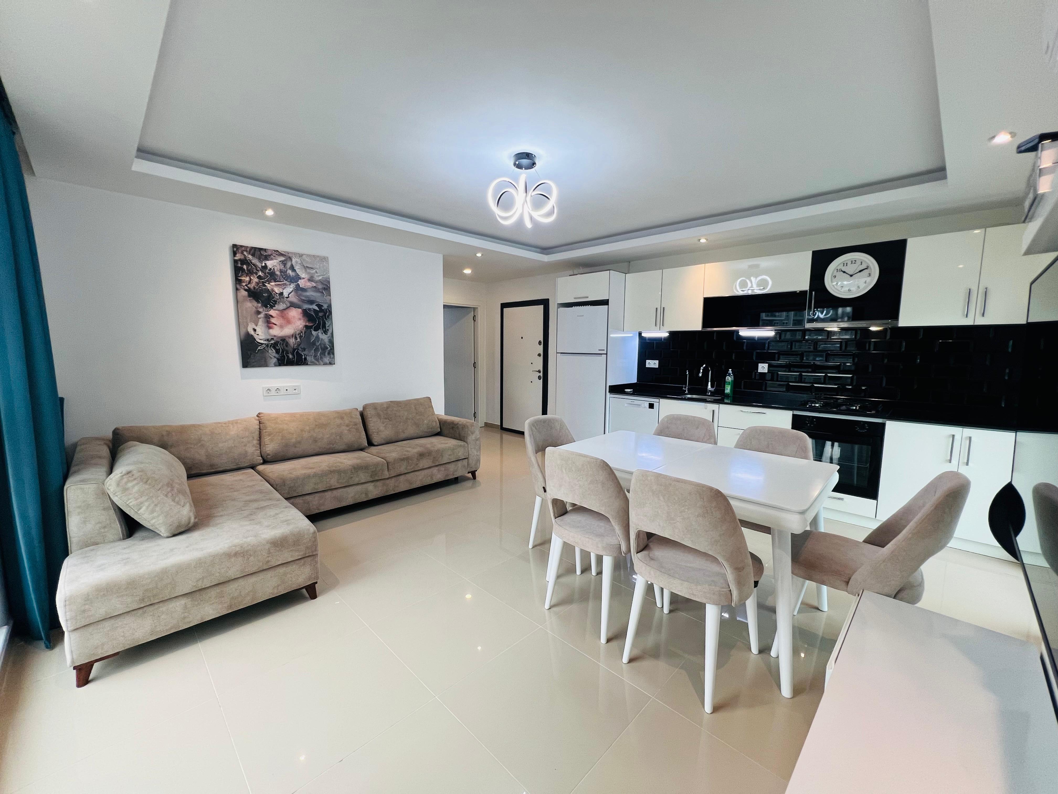 Kitchen-living room with a beige sofa and white table in an apartment in Avsallar where a flat is for sale