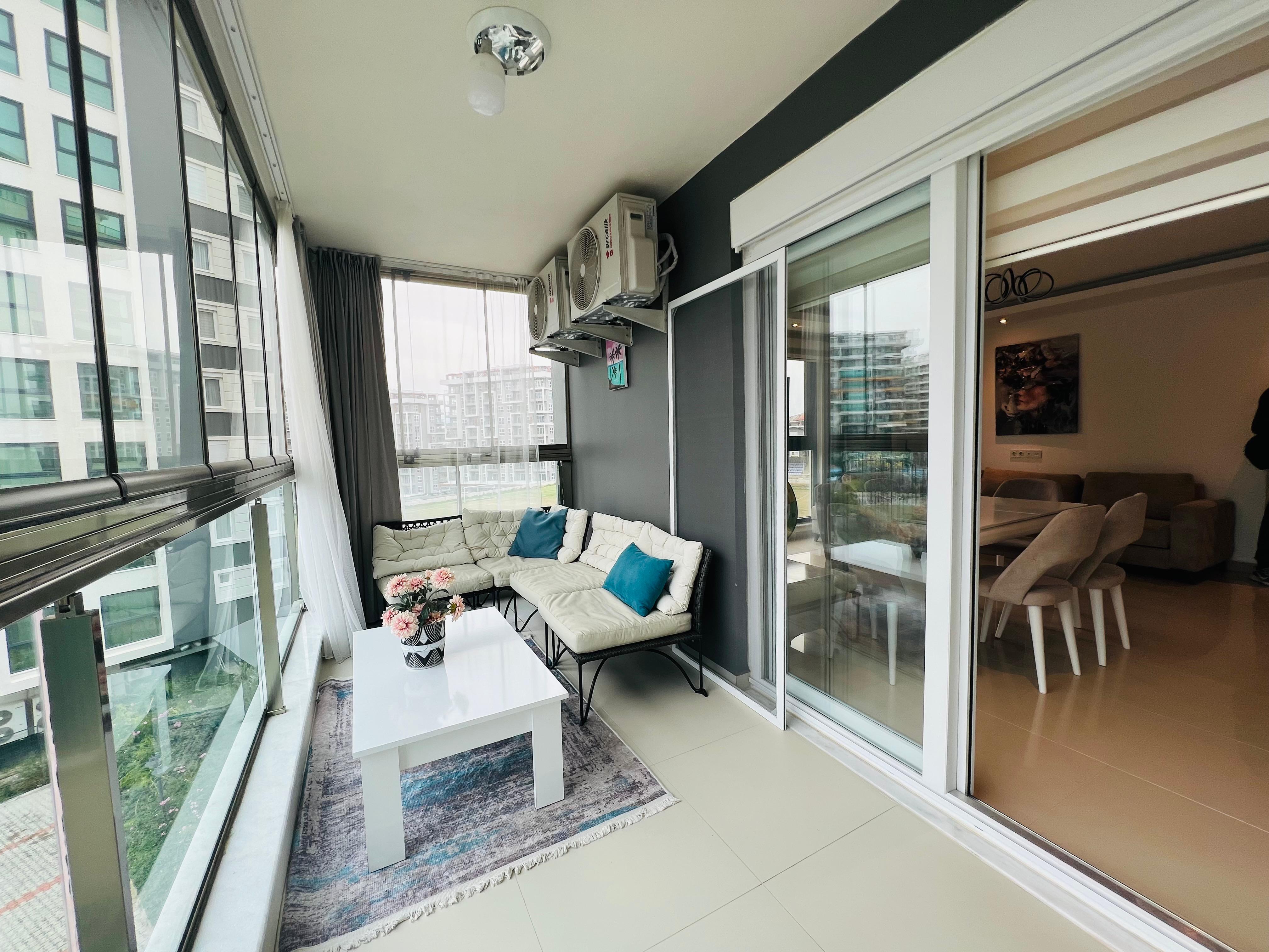 Glazed loggia with a white sofa and views of residential buildings and the courtyard
