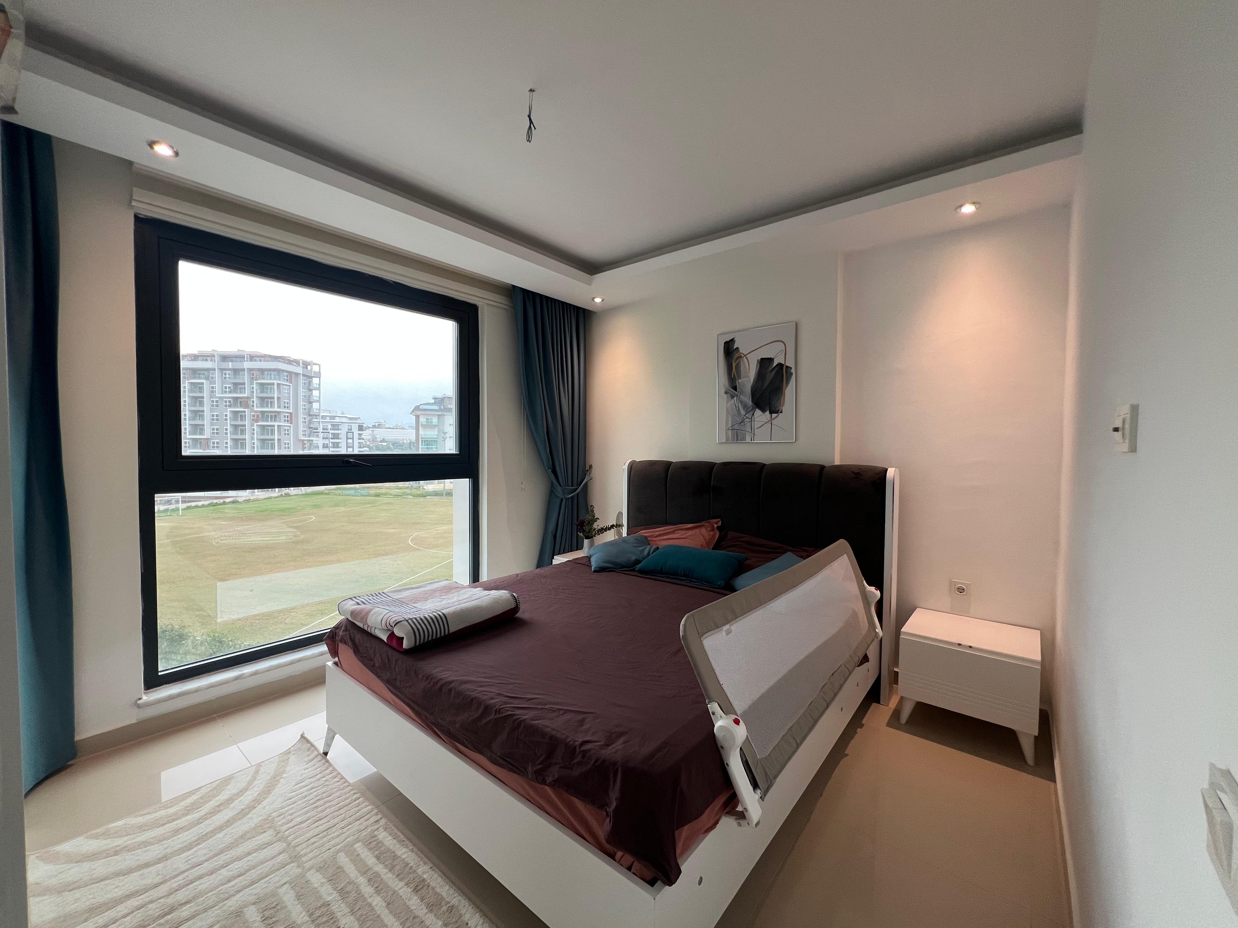 Bedroom with a double bed dark blue curtains and a panoramic window in an apartment