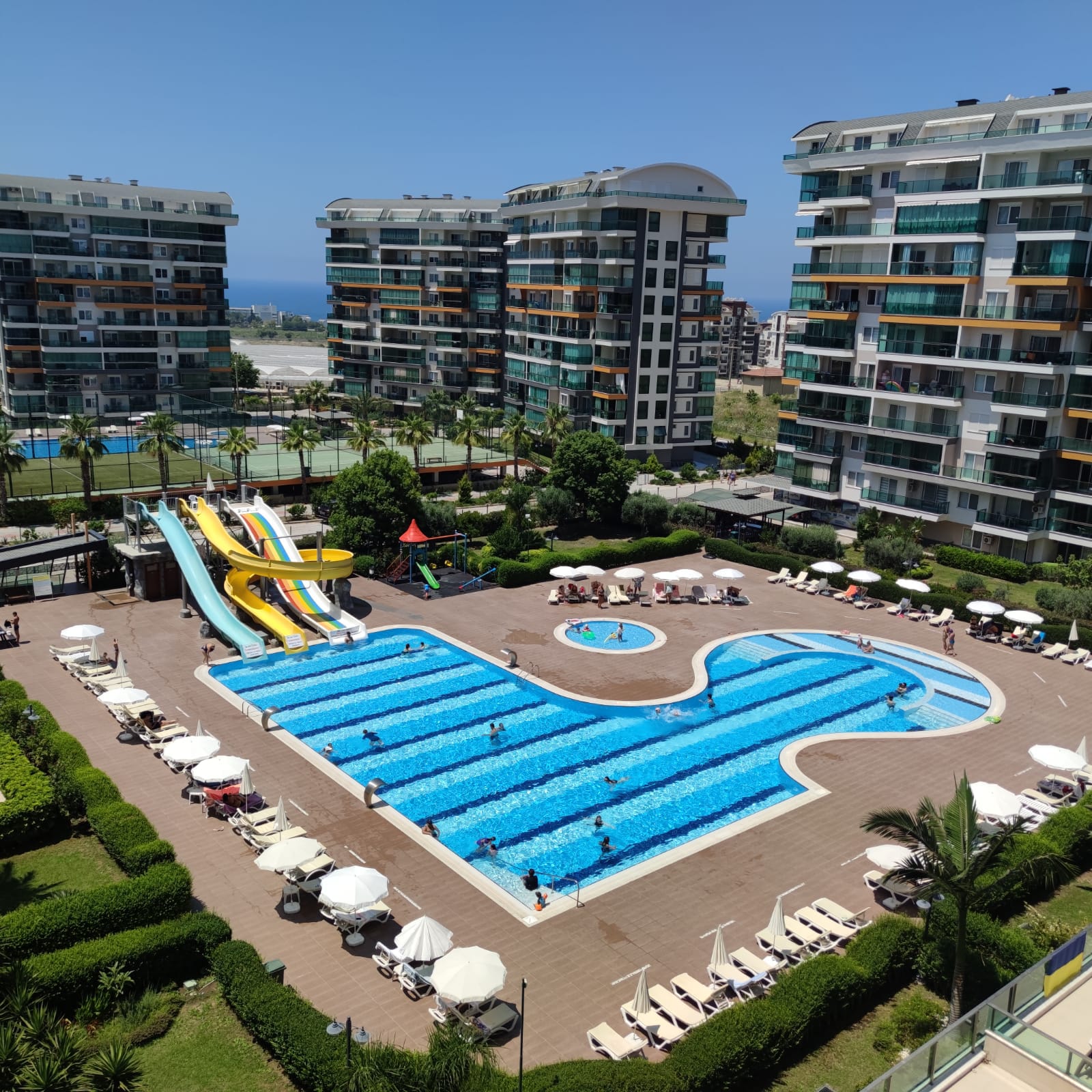 Large shaped outdoor pool with slides and a play area at an apartment complex in Avsallar