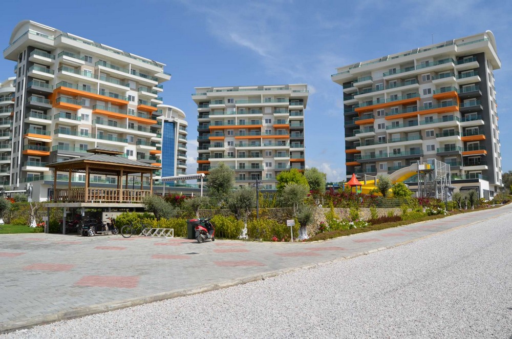 Red-tiled walkway and covered gazebo beside residential buildings with apartments for sale