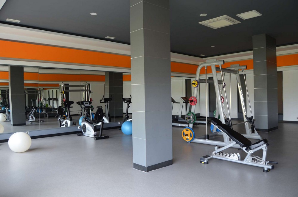 Gym with a multifunctional strength machine and exercise bikes in a complex with apartments