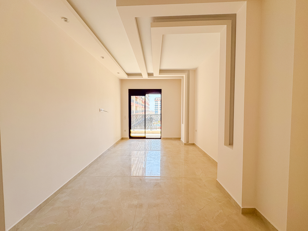 Mahmutlar’daki konutun uzun yatak odasında siyah çerçeveli balkon kapısı ve geometrik tavan