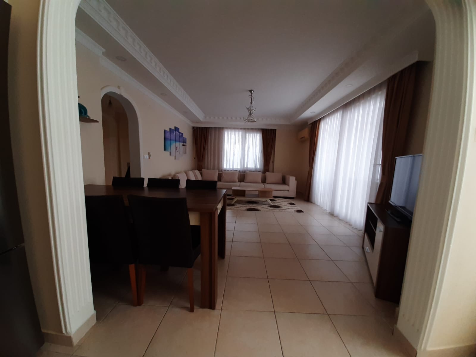 Mahmutlar’daki 2+1 dairenin salonunda köşe koltuk, yemek masası ve panoramik pencereler
