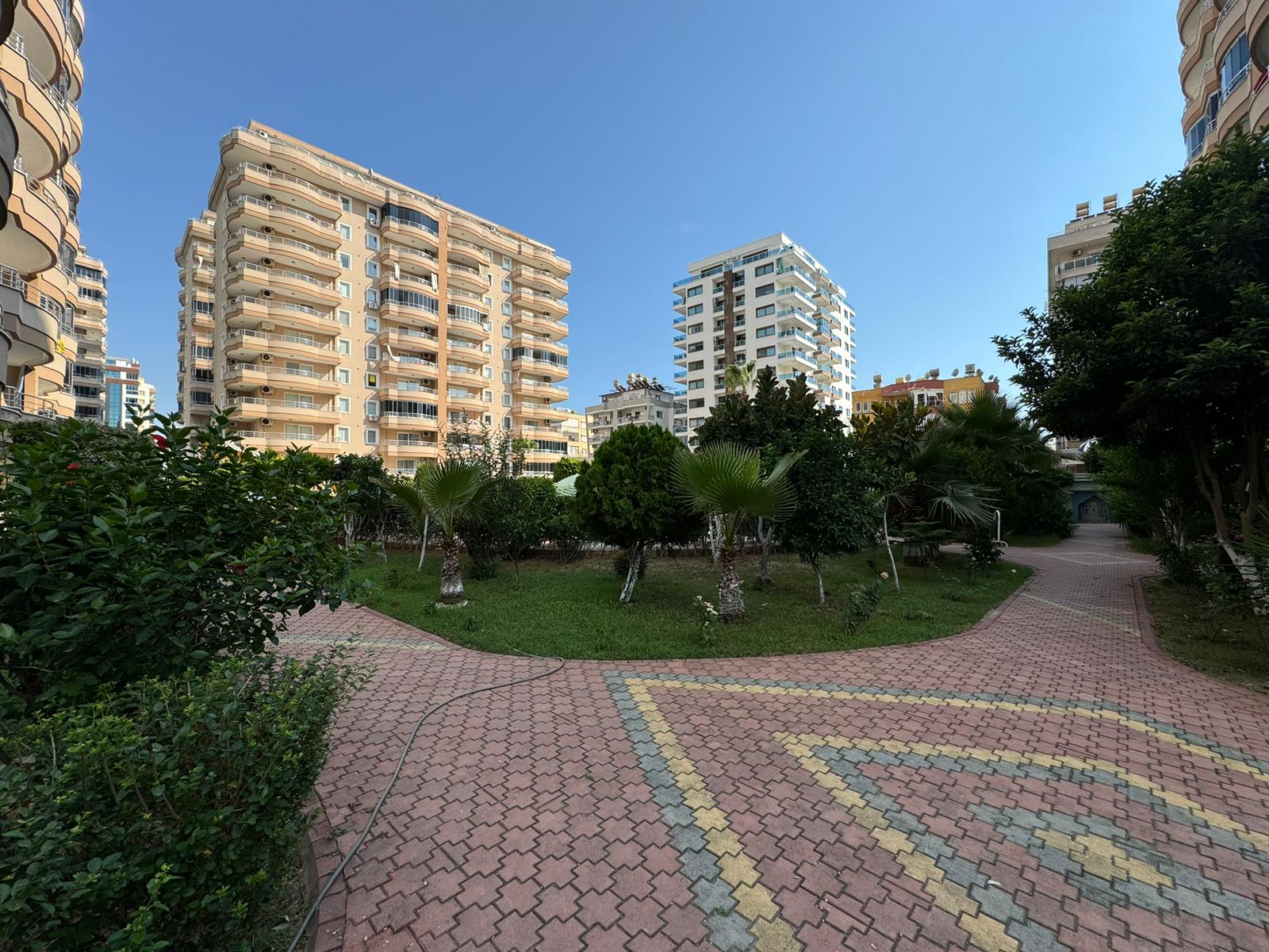 Türkiye’de satılık dairelerin bulunduğu sitede palmiyeli kıvrımlı bahçe yolu