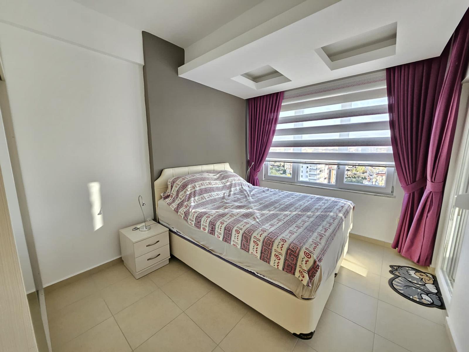 Penthouse yatak odasında çift kişilik yatak, gömme dolap ve stor perdeli panoramik pencere