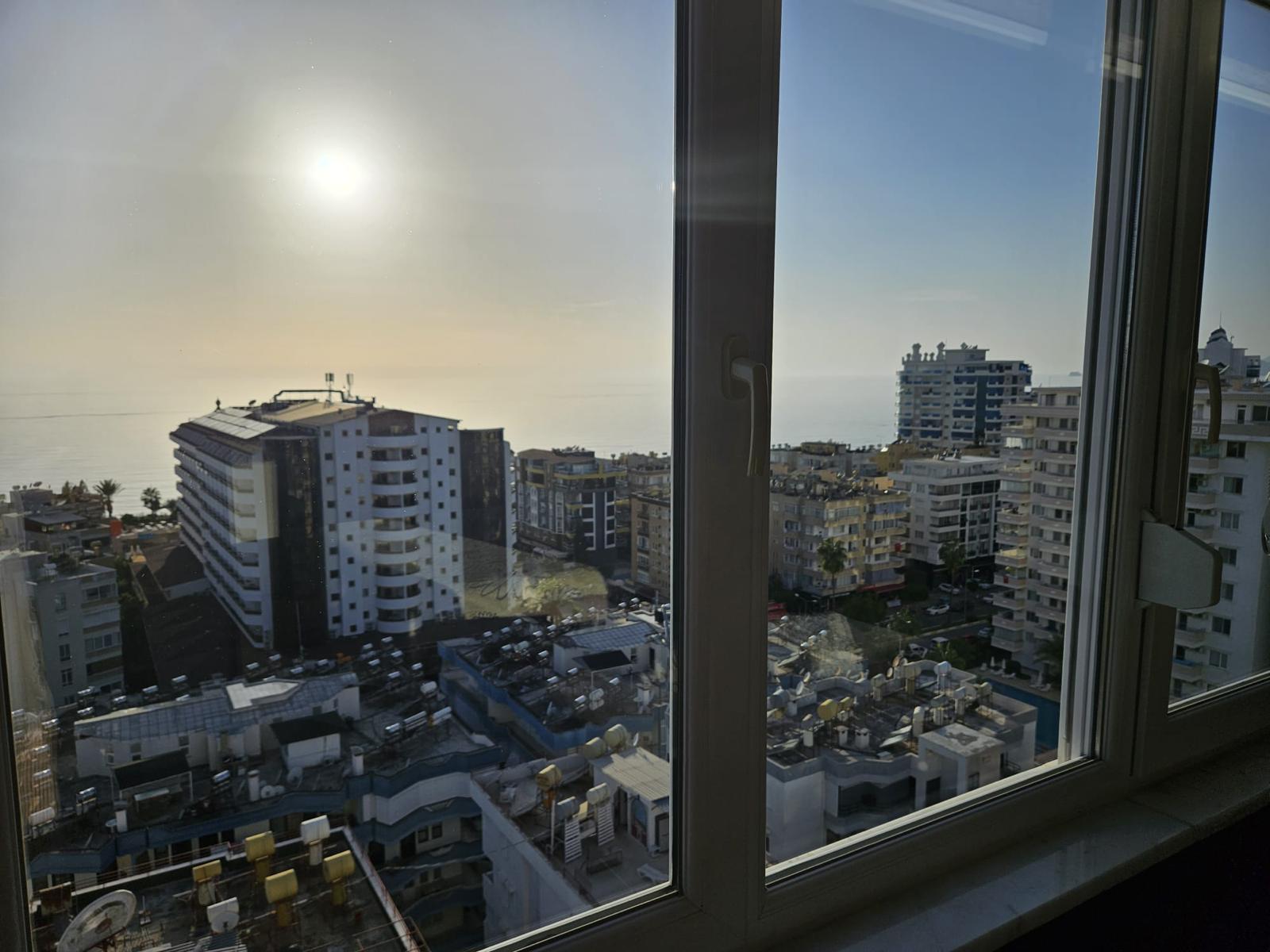 Türkiye’de satılık rezidansın köşe panoramik penceresinden şehir ve ufuktaki deniz manzarası