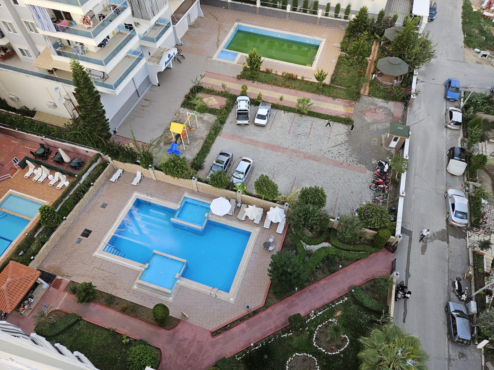 Mahmutlar’daki penthouse dairelerin bulunduğu yerleşimde çocuk havuzlu açık havuz ve şezlonglu teras