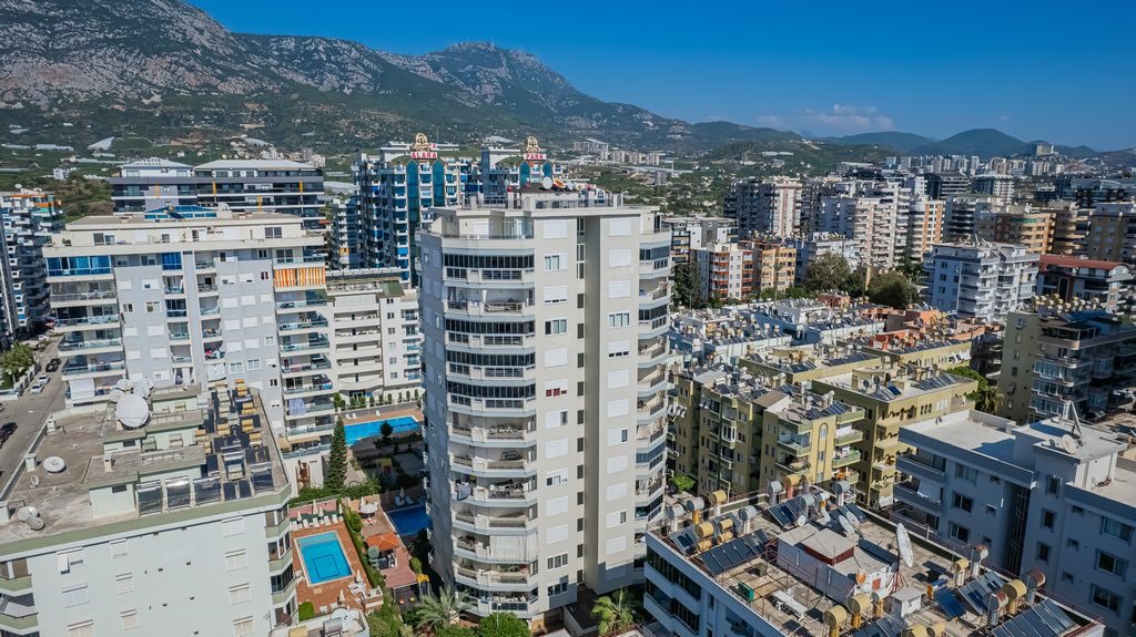 Güneş panelleri bulunan çatılar ve avlu havuzu önünde dağ manzaralı Türkiye’de satılık penthouse