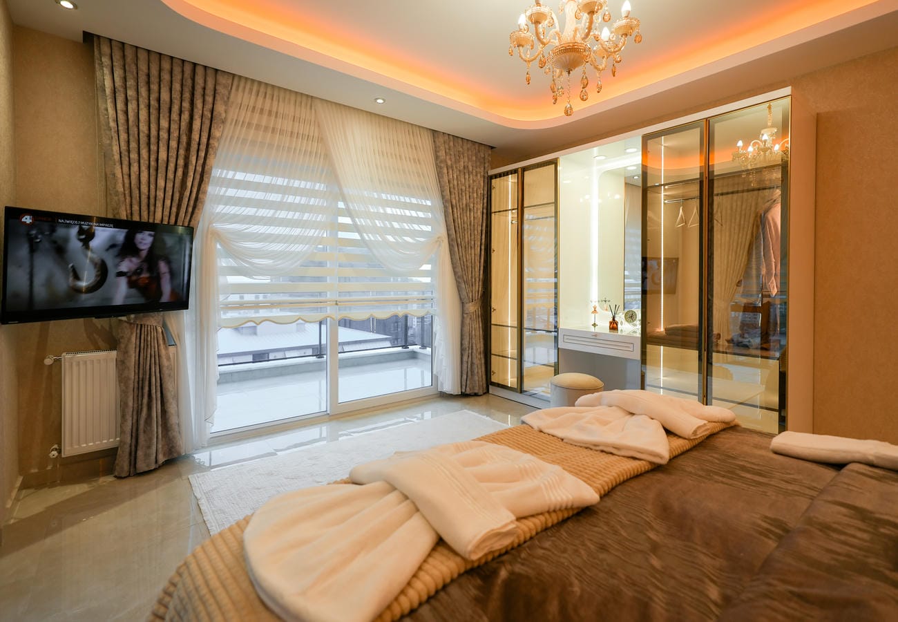 Mahmutlar’daki yatak odasında balkon sürgülü cam kapısı ve kahverengi örtülü yatak