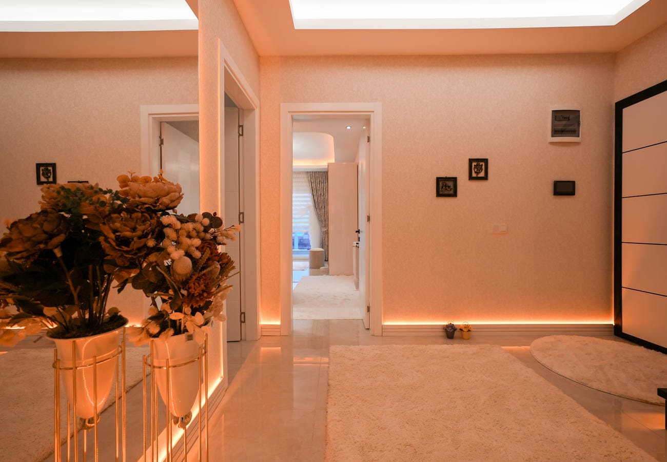 Mahmutlar’daki penthouse antrede geniş halı alanı ve çiçek düzenlemeli alçak konsol