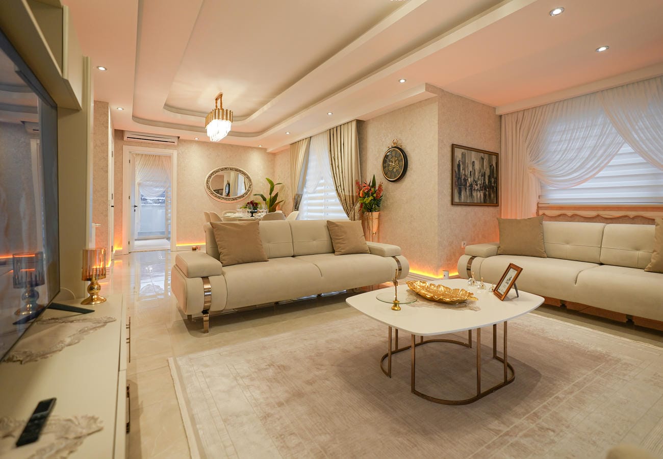 Türkiye’de satılık penthouse salonunda oval beyaz sehpa ve duvar televizyonu