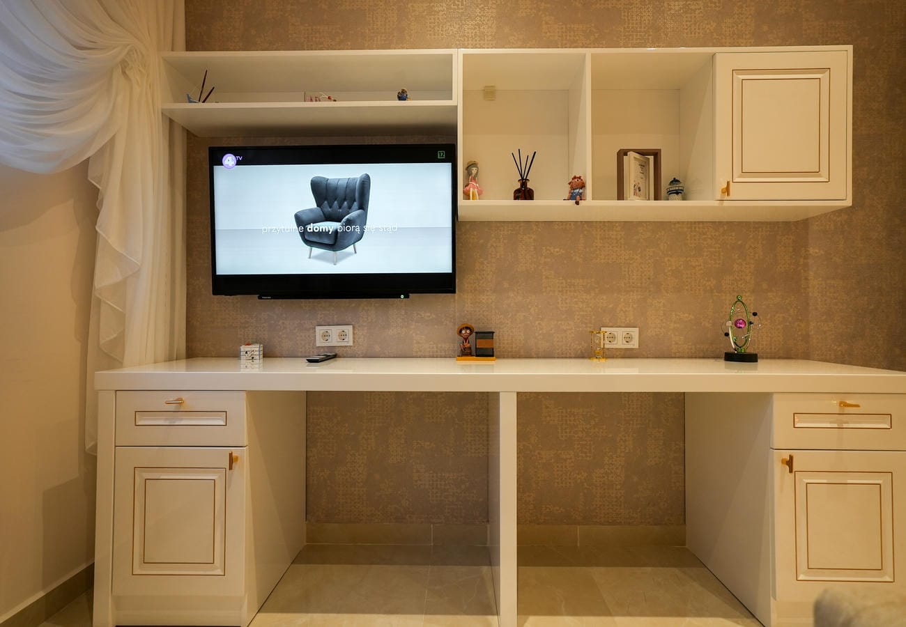 Penthouse salonunda altın renk kulplu beyaz TV ünitesi, açık raflar ve dokulu bej duvar kâğıdı
