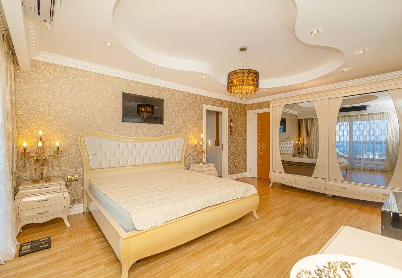 Спальня с двуспальной кроватью, зеркальным шкафом и янтарным подвесным светильником