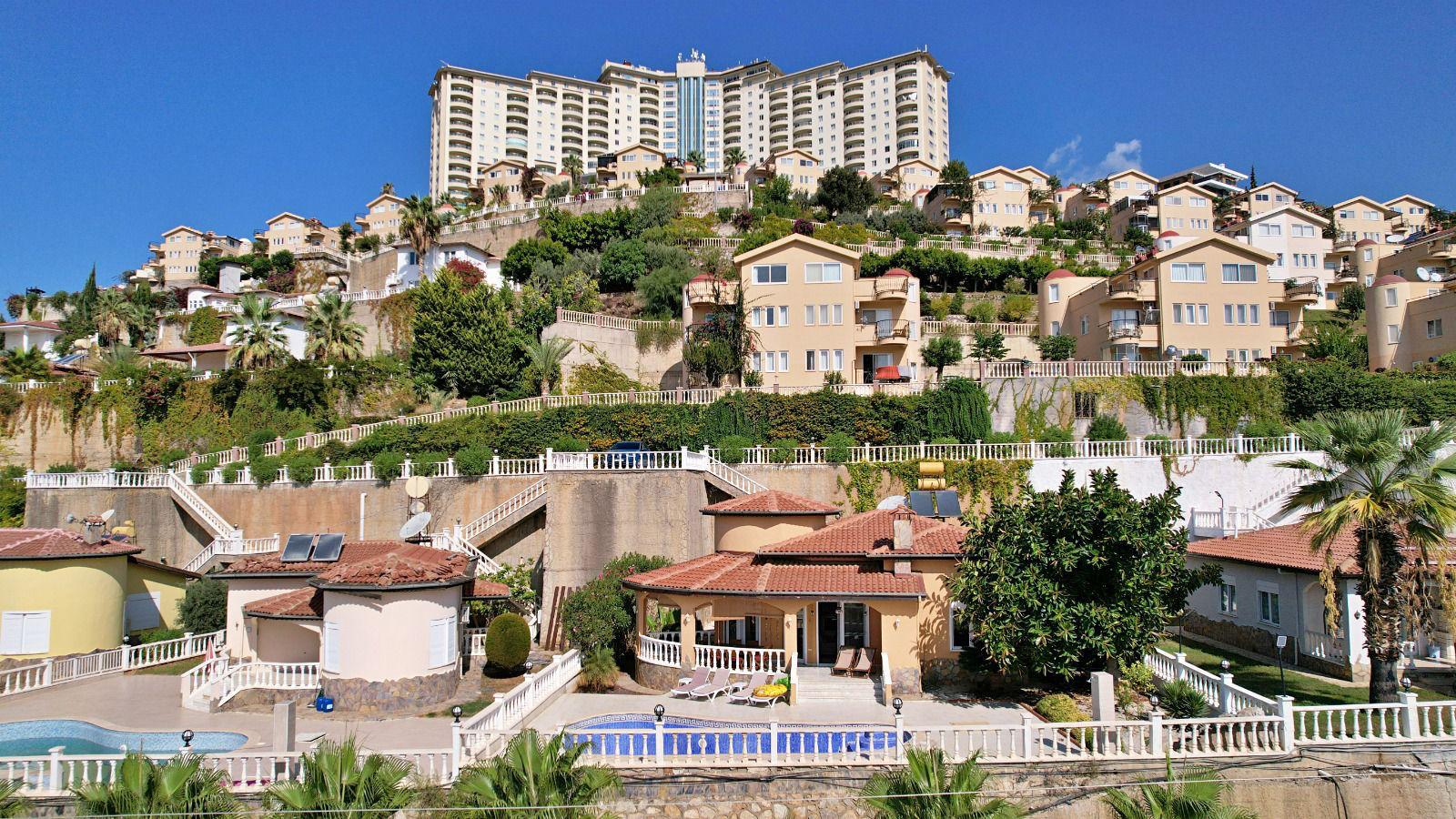 Rows of villas for sale in Mahmutlar line a terraced slope with private pools and mountain views