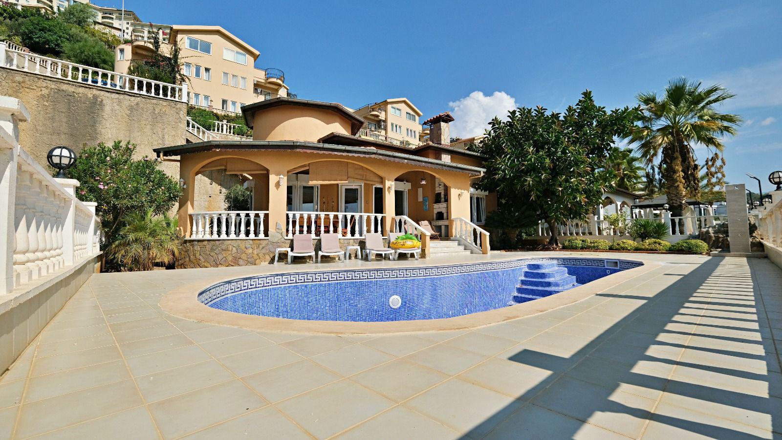 Arched openings on a covered terrace beside an oval pool in Mahmutlar, Turkey
