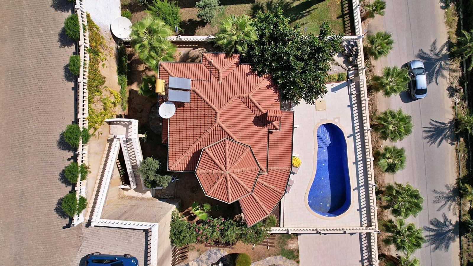 Top view of a villa with red tile roof and oval pool in Mahmutlar, with solar panels