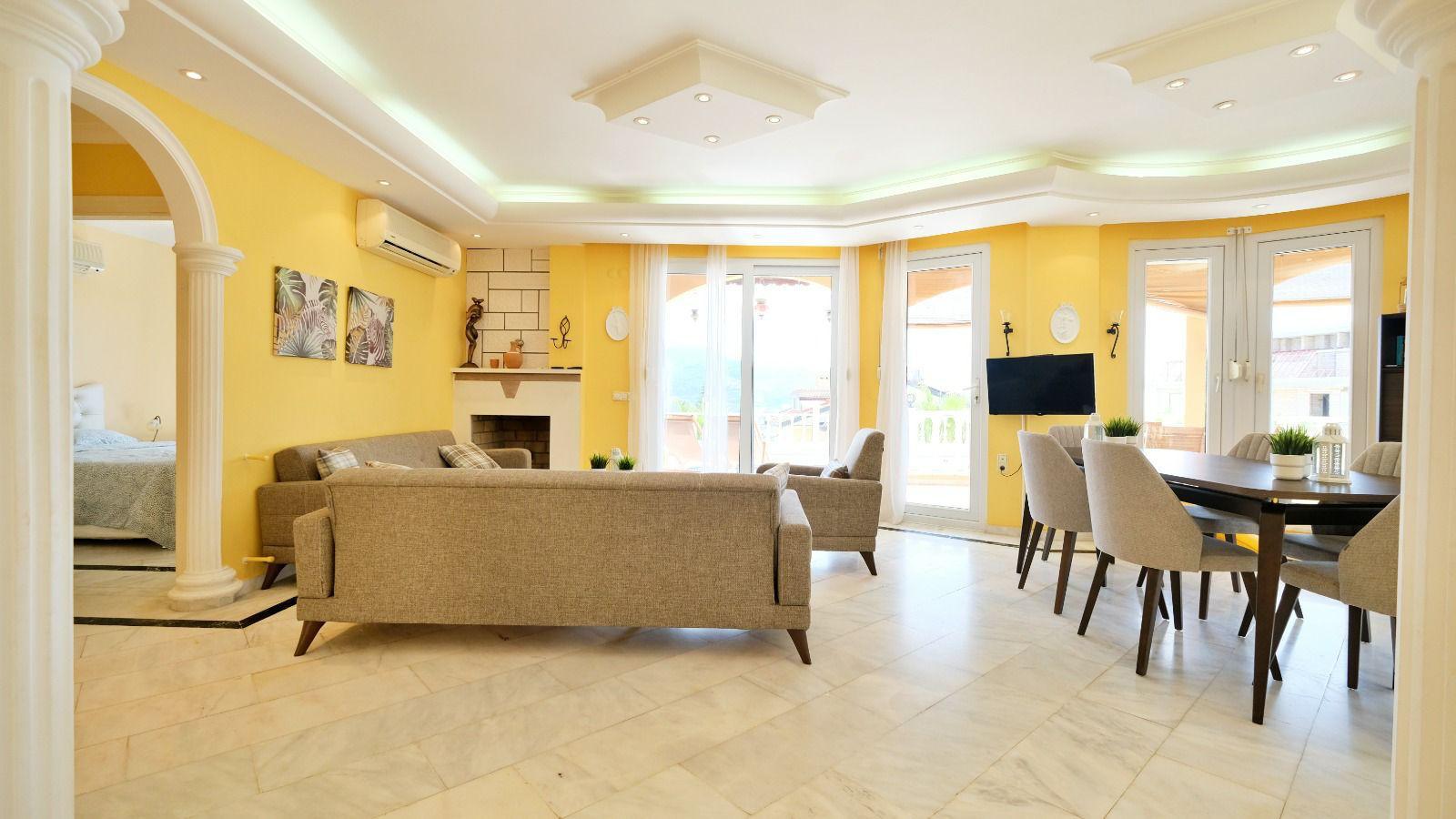 Dining area in a house with upholstered chairs, gray sofa and decorative fireplace