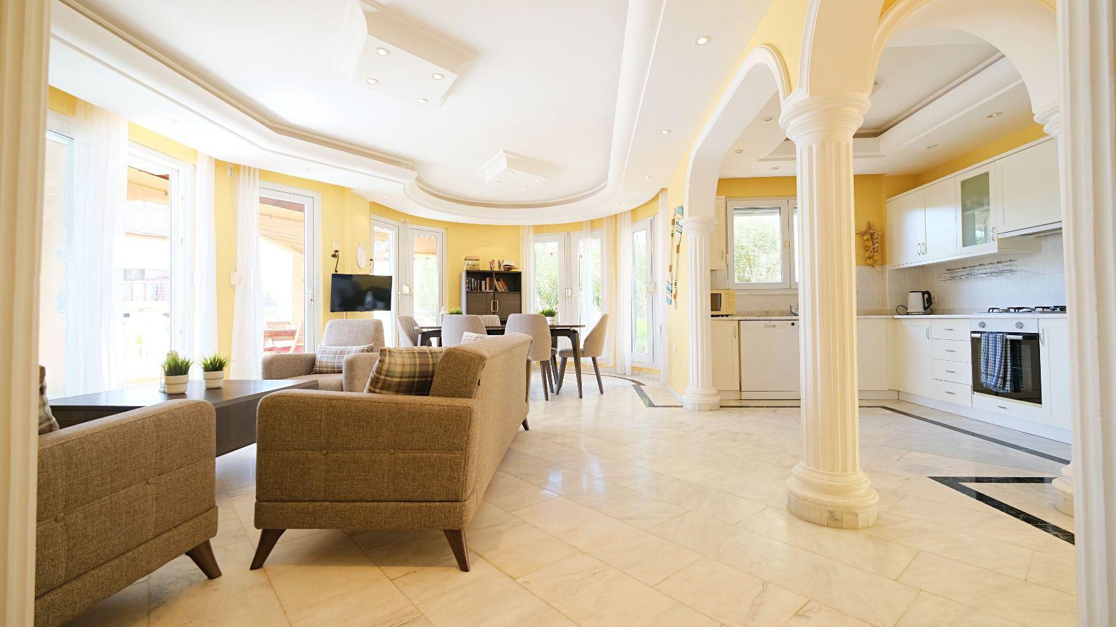 Gray seating, white kitchen and marble floor in a home offered for sale