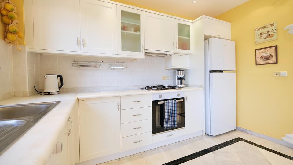 Kitchen with white cabinets, fridge, coffee maker and kettle in Mahmutlar