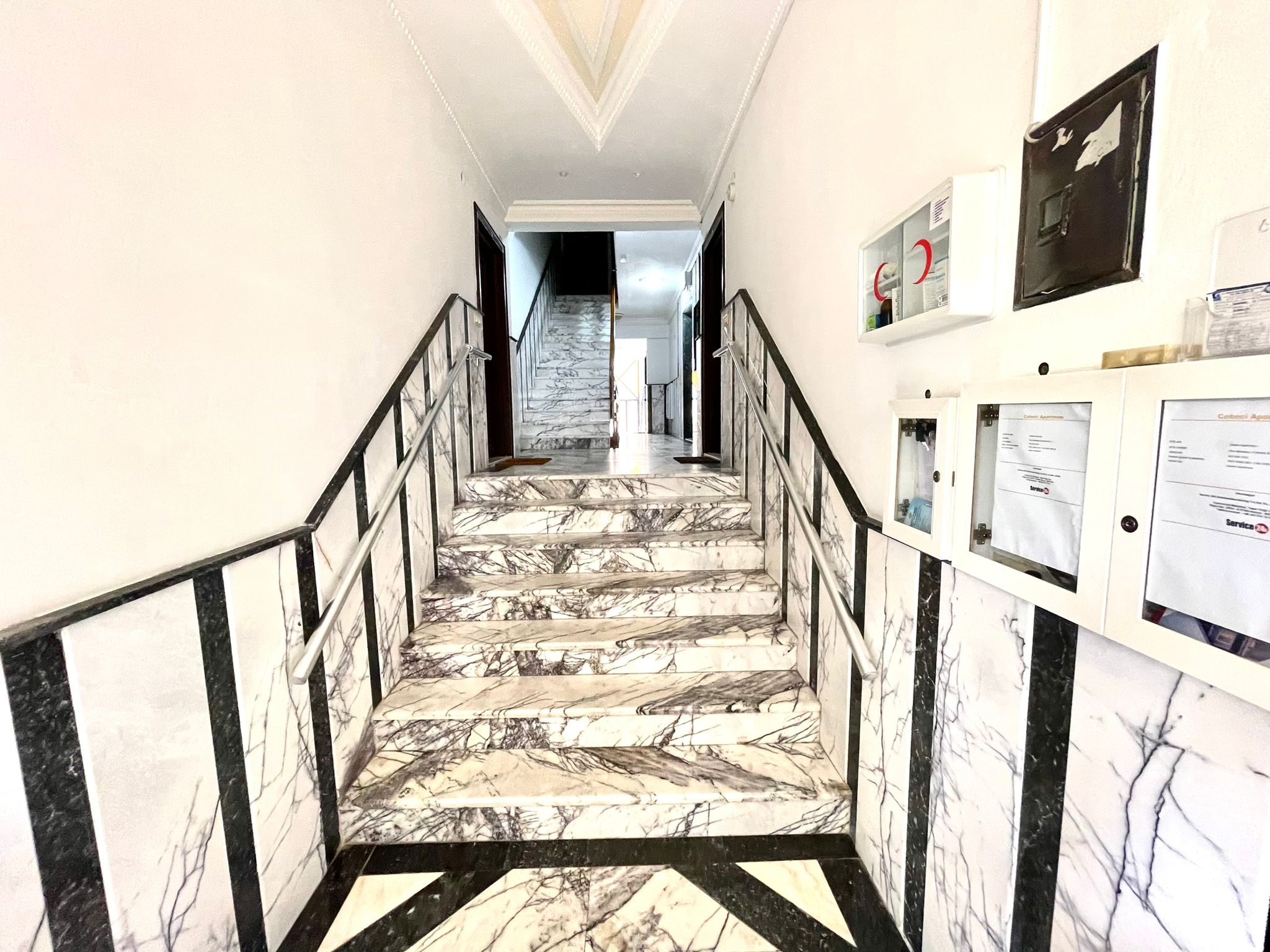 Mermer merdivenli giriş holünde, Oba'daki rezidansın siyah beyaz geometrik zemini ve posta kutuları