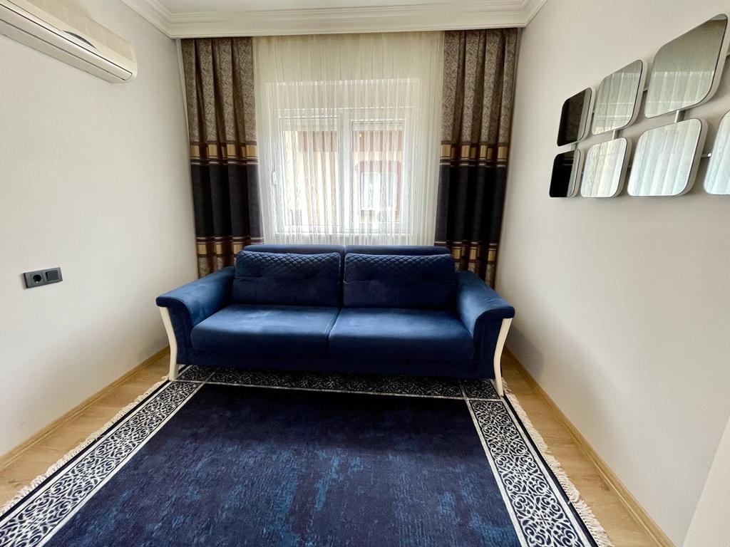 Oba'daki Türkiye konutunun küçük salonunda mavi ikili kanepe ve aynalı panel düzenlemesi