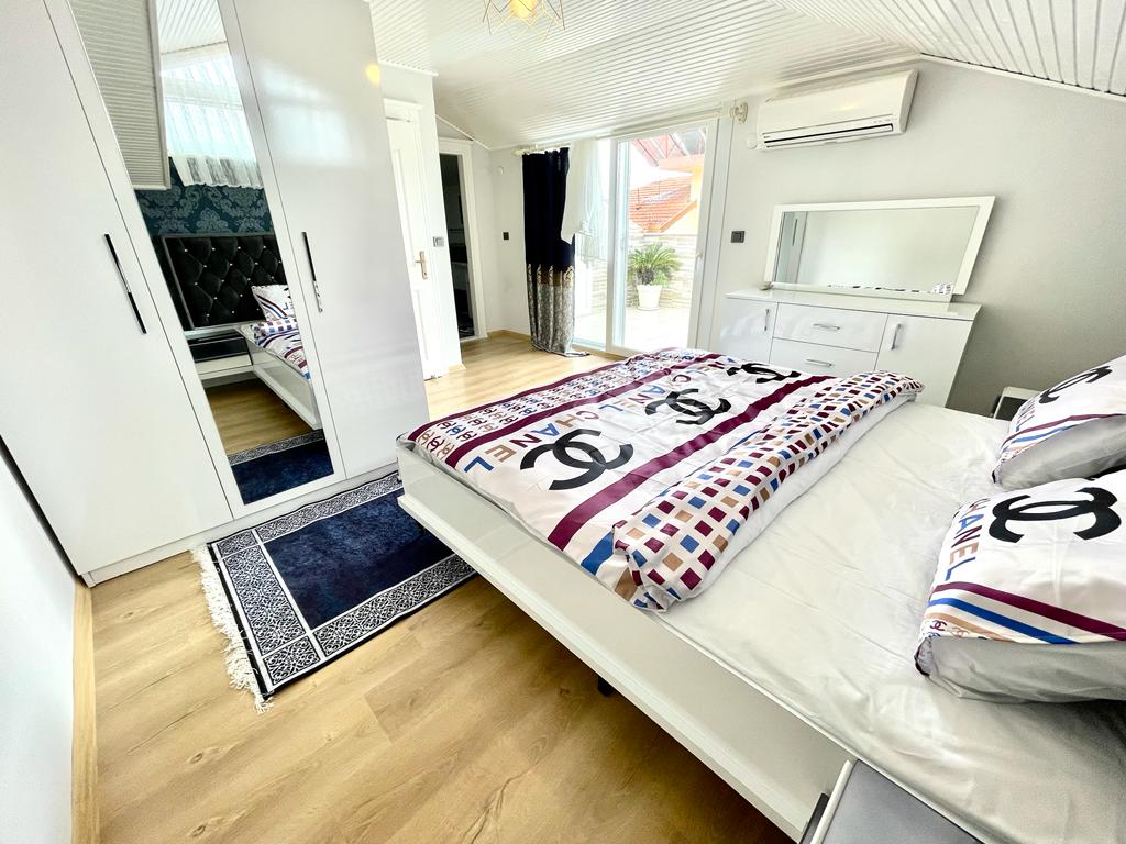Alanya'daki dubleksin yatak odasında aynalı beyaz dolap ve balkona açılan cam kapı