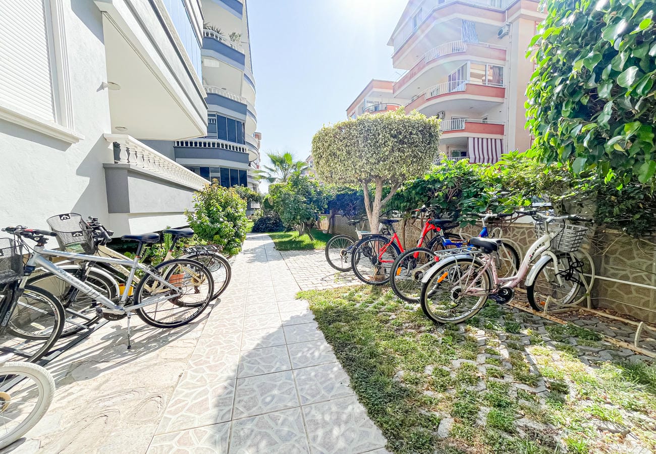 Bisikletlerin sıralandığı avlu, Oba’daki daire sakinleri için çit ve yuvarlak budanmış ağaçla