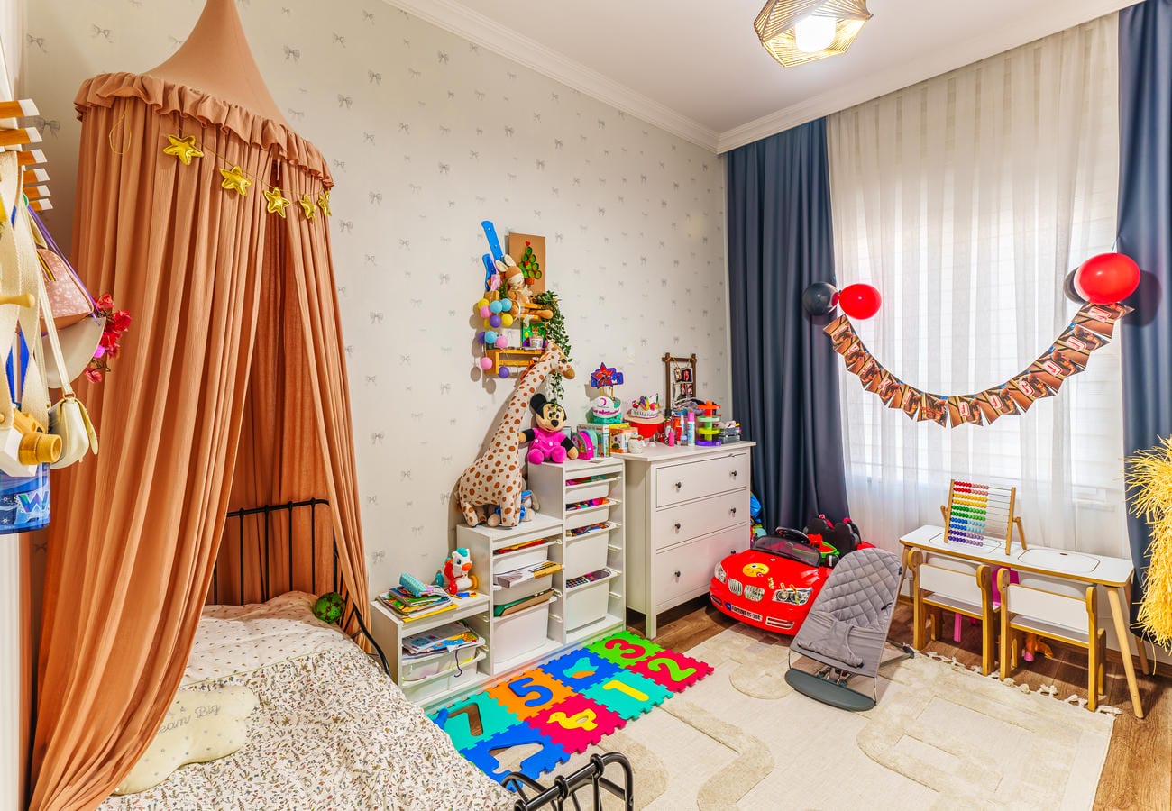 Çocuk odasında cibinlikli yatak, oyuncaklar ve renkli yapboz halı, Oba’da 3+1 dairede