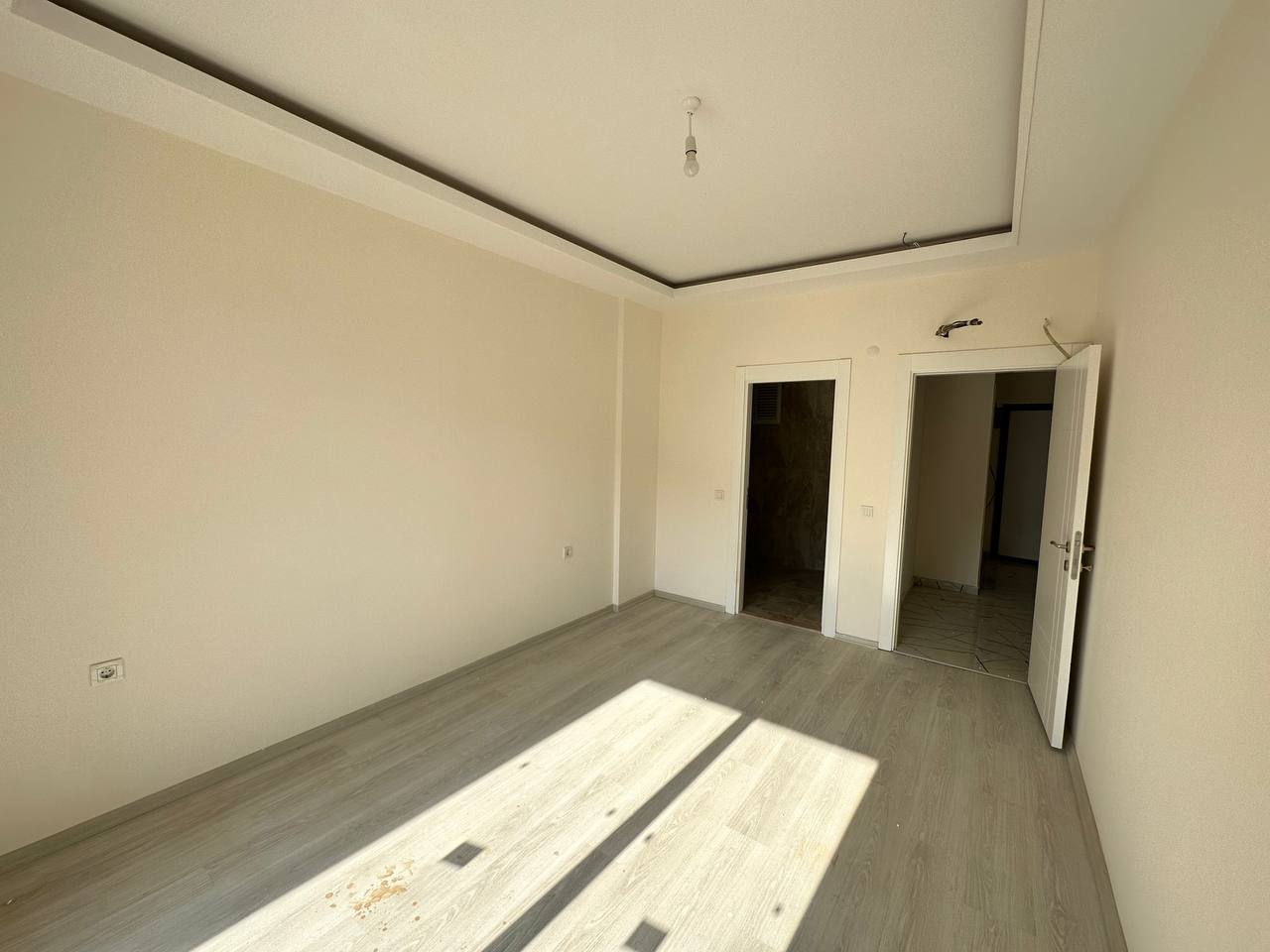 Açık iç kapılı salon, Oba’daki dairede açık laminat zemin ve koridora geçişle