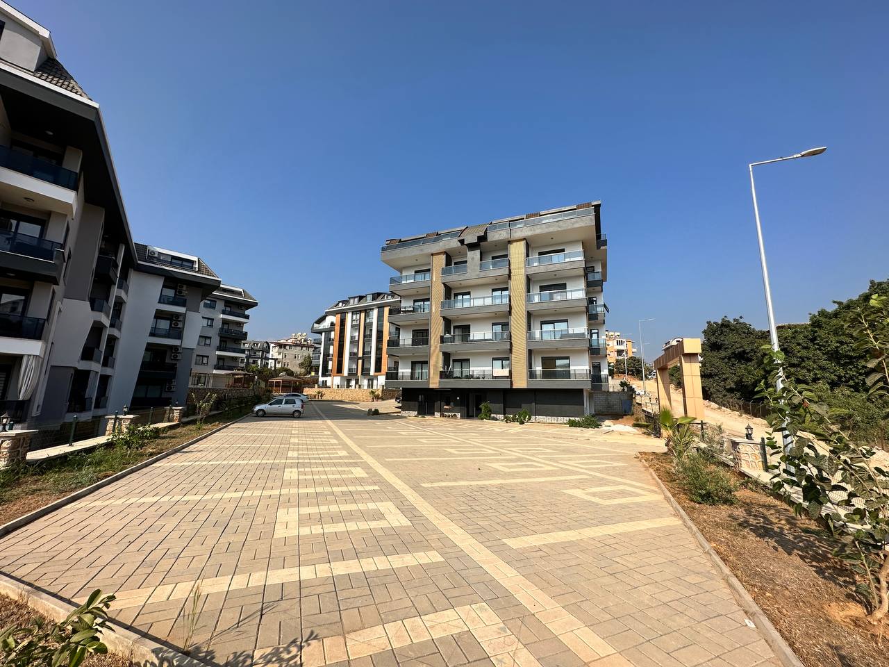 Cam balkonlu çok katlı bina, satılık dairelerin yer aldığı sitede geniş taş döşeli otoparkla