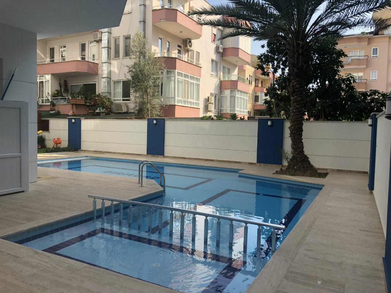 Sığ bölümü ve metal merdiveni olan havuz, satılık dairelerin bulunduğu sitede