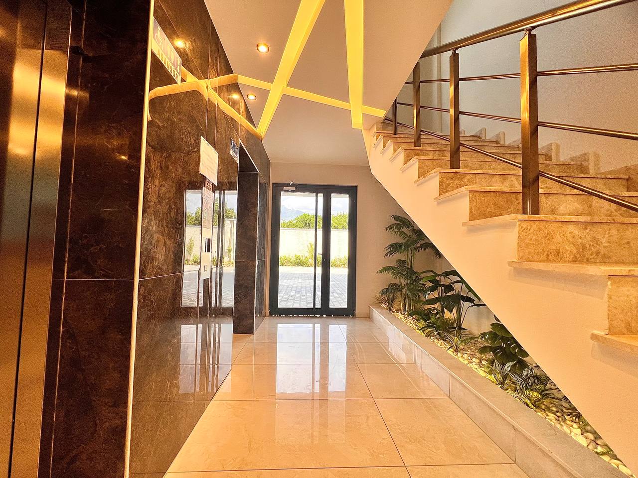 Apartman sakinleri için lobide mermer basamaklı merdiven ve aynalı asansör kapıları